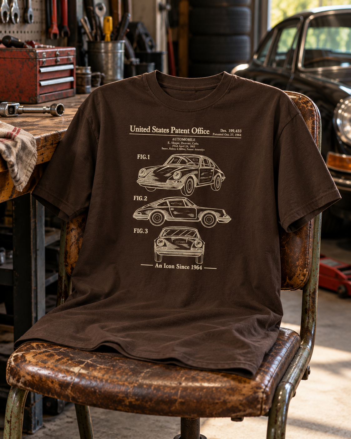 Dark chocolate 1964 automobile patent T-shirt draped over a vintage workshop chair beside automotive tools