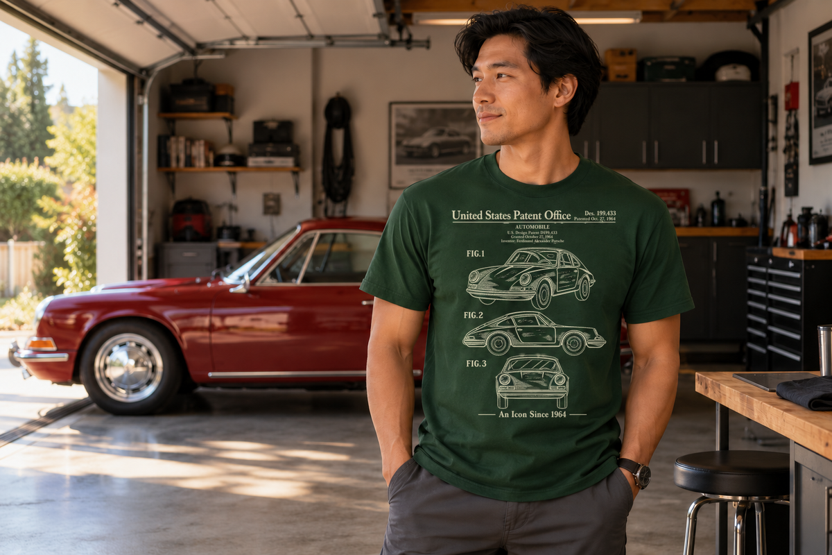 Man wearing the forest green 1964 automobile design patent T-shirt in a home garage with a classic red Porsche 911 parked toward the open door