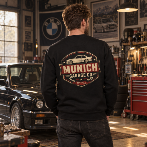 Man wearing black Munich Garage Co. BMW sweatshirt in a vintage German sports car workshop