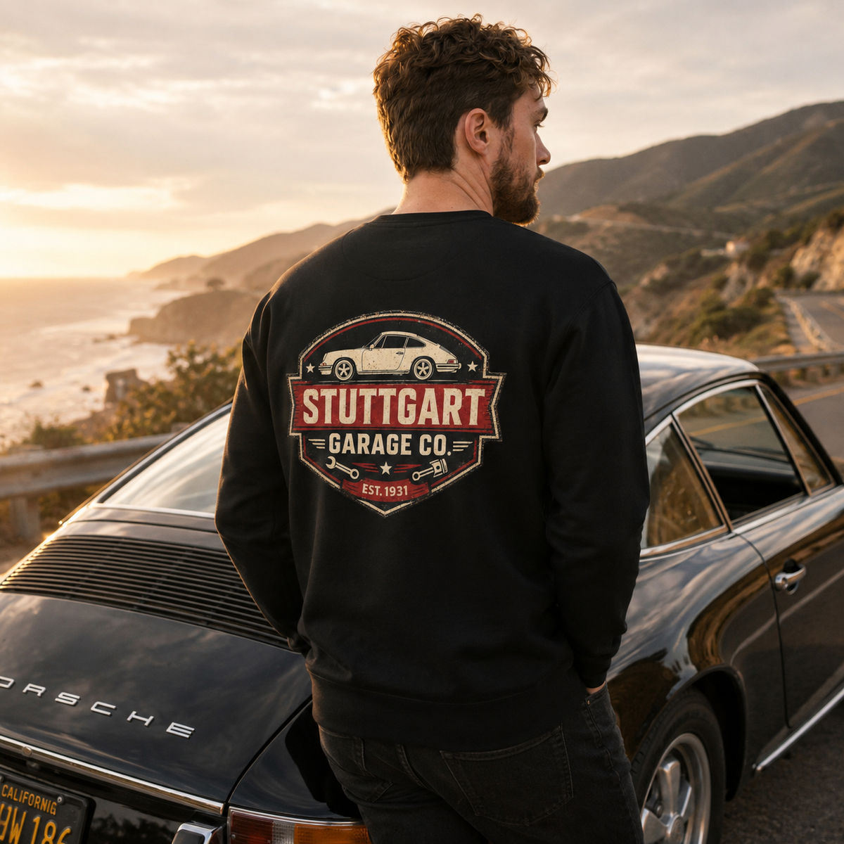 Black Stuttgart Garage Co. sweatshirt worn beside a classic Porsche on a golden-hour coastal drive