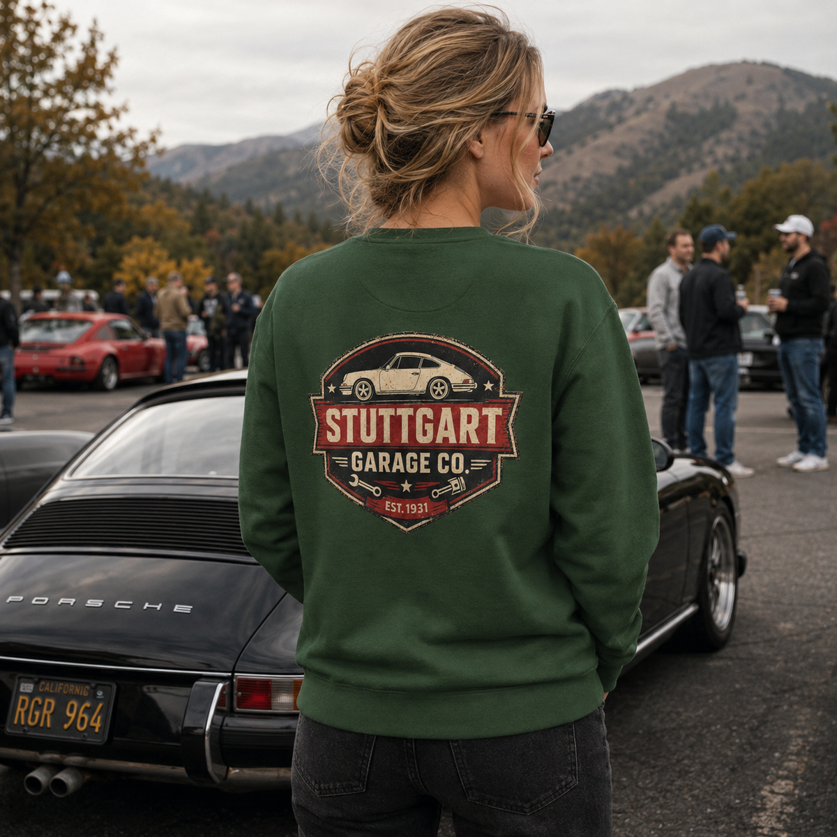 Woman wearing forest green Stuttgart Garage Co. sweatshirt at a mountain cars and coffee meet