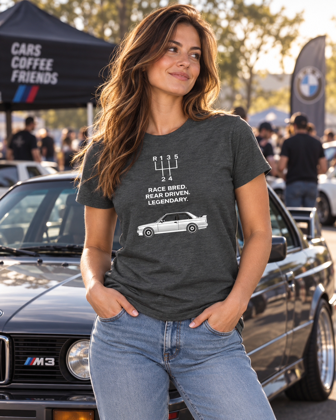 Female model wearing gray E30 M3 Tribute T-Shirt at a cars-and-coffee automotive lifestyle event