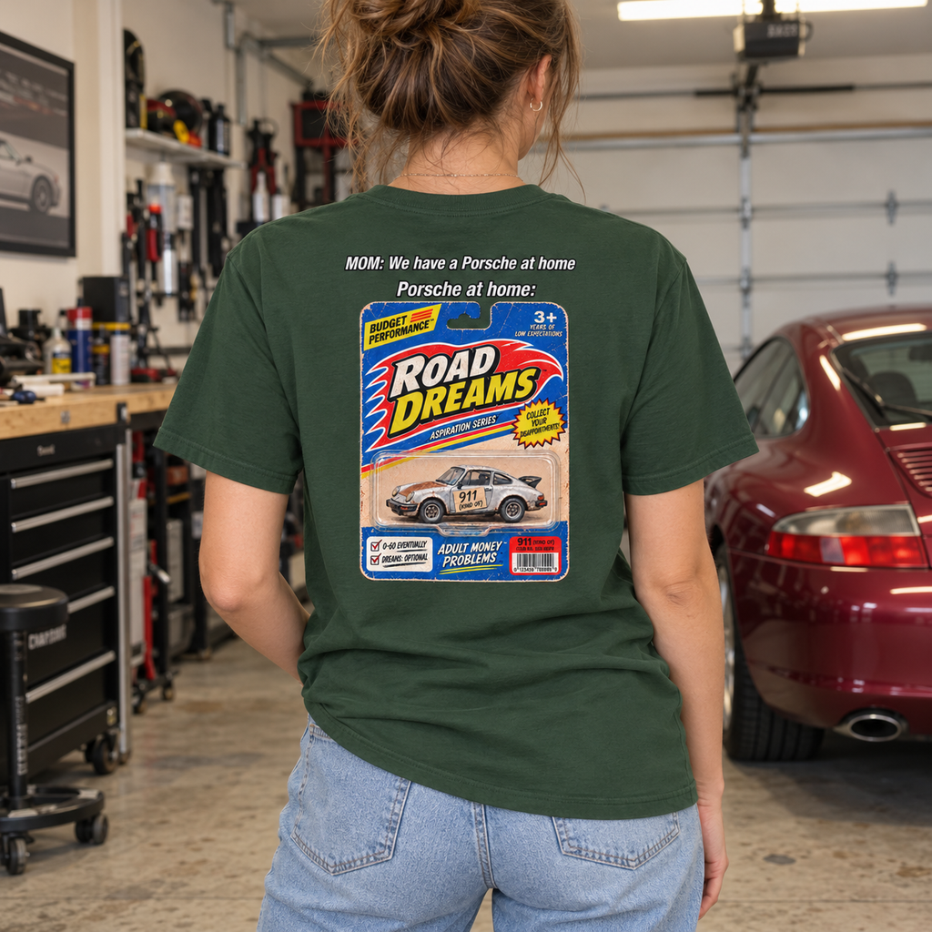 Woman wearing forest green Porsche at Home T-shirt in a home garage, showing the retro Road Dreams back design