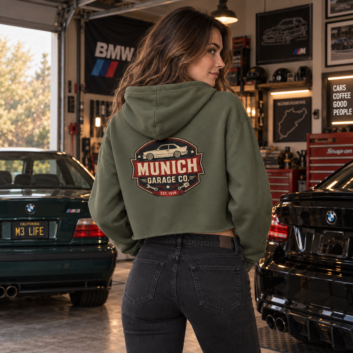 Back view of woman wearing Military Green Munich Garage Co. cropped hoodie with vintage German car graphic on the back.