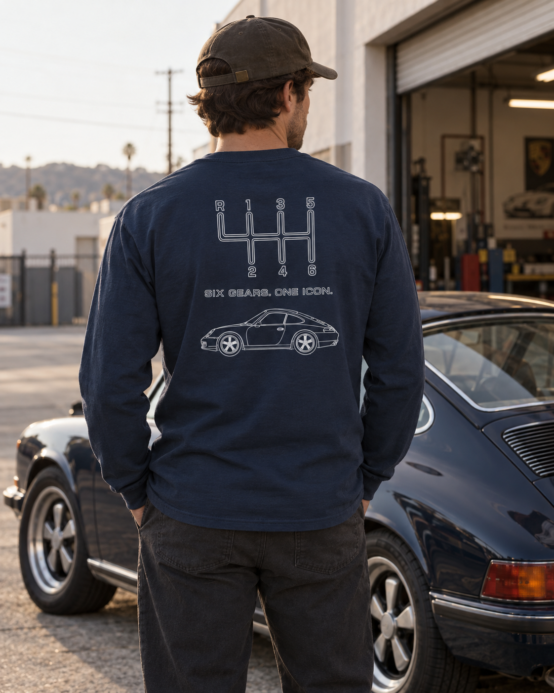 Navy manual transmission long sleeve shirt with Six Gears One Icon back graphic in an automotive lifestyle setting