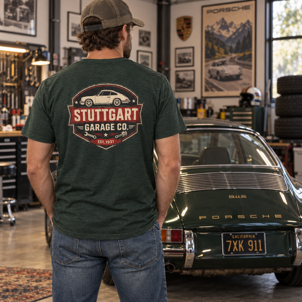 Man wearing Heather Emerald Stuttgart Garage Co. T-shirt with vintage back graphic in a Porsche garage setting