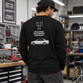 Man wearing black E30 M3 tribute heavyweight long sleeve in a garage, showing Race Bred Rear Driven Legendary back print