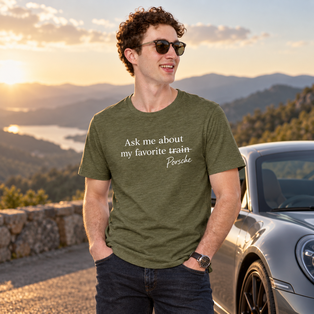 Model wearing olive Porsche humor T-shirt beside sports cars during a golden-hour drive