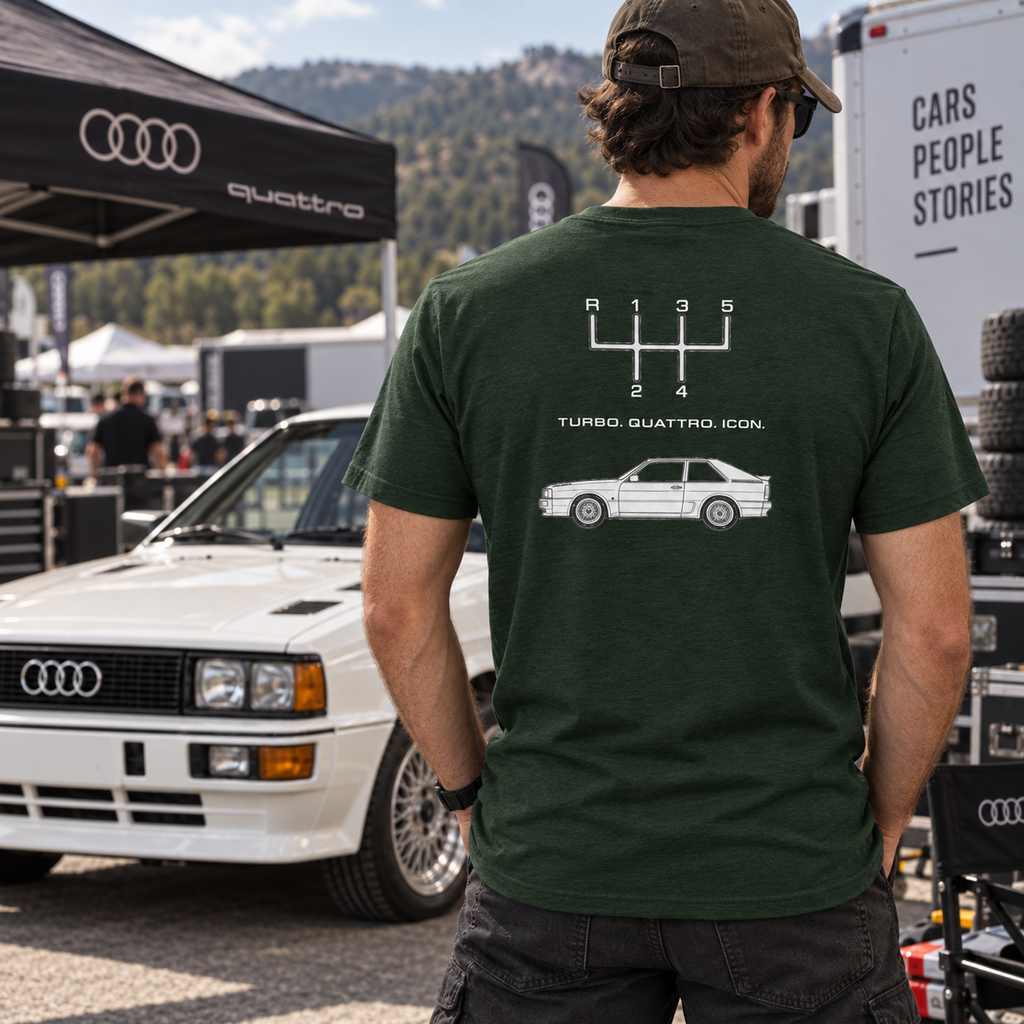 Man wearing Heather Emerald Audi Quattro T-shirt showing the rear graphic beside a classic Audi coupe
