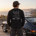 Black manual transmission long sleeve shirt with Six Gears One Icon back graphic at a coastal overlook