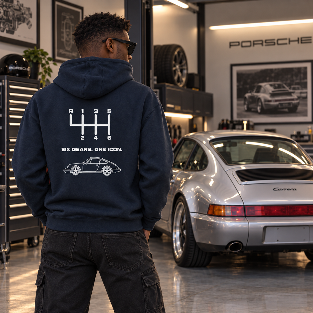 Man wearing blue manual transmission hoodie in a garage, showing white automotive back graphic