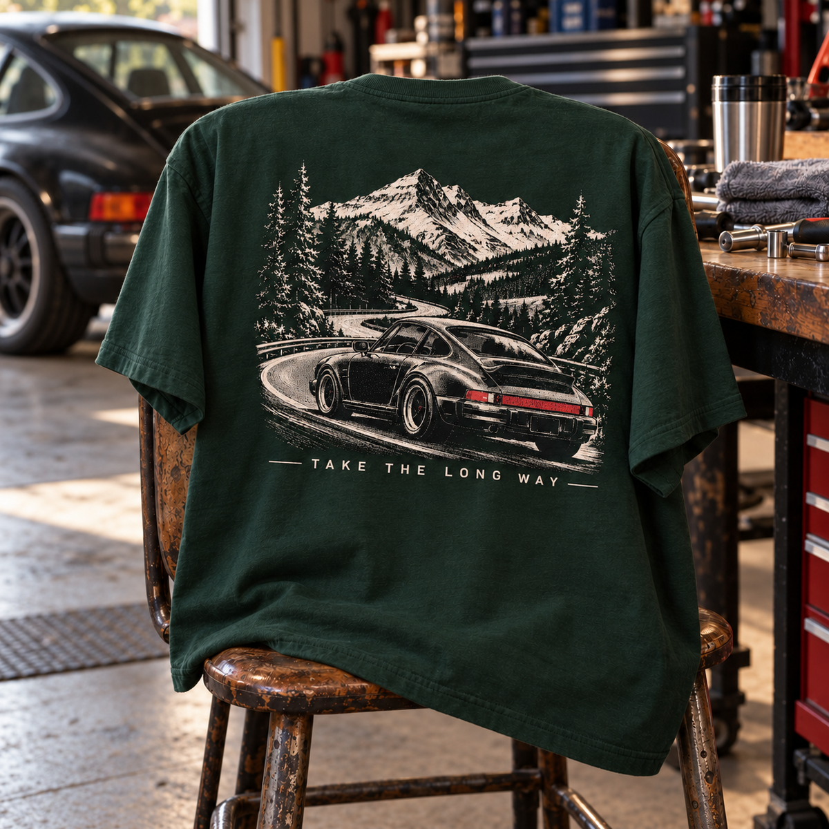 Forest Green Take The Long Way T-shirt back graphic draped on vintage garage chair by workbench
